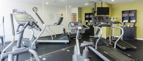 Un gimnasio con cintas de correr, elípticas y una máquina de remo.