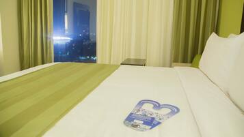 Une chambre d’hôtel avec un lit, une table de chevet et une vue sur le paysage urbain par la fenêtre.