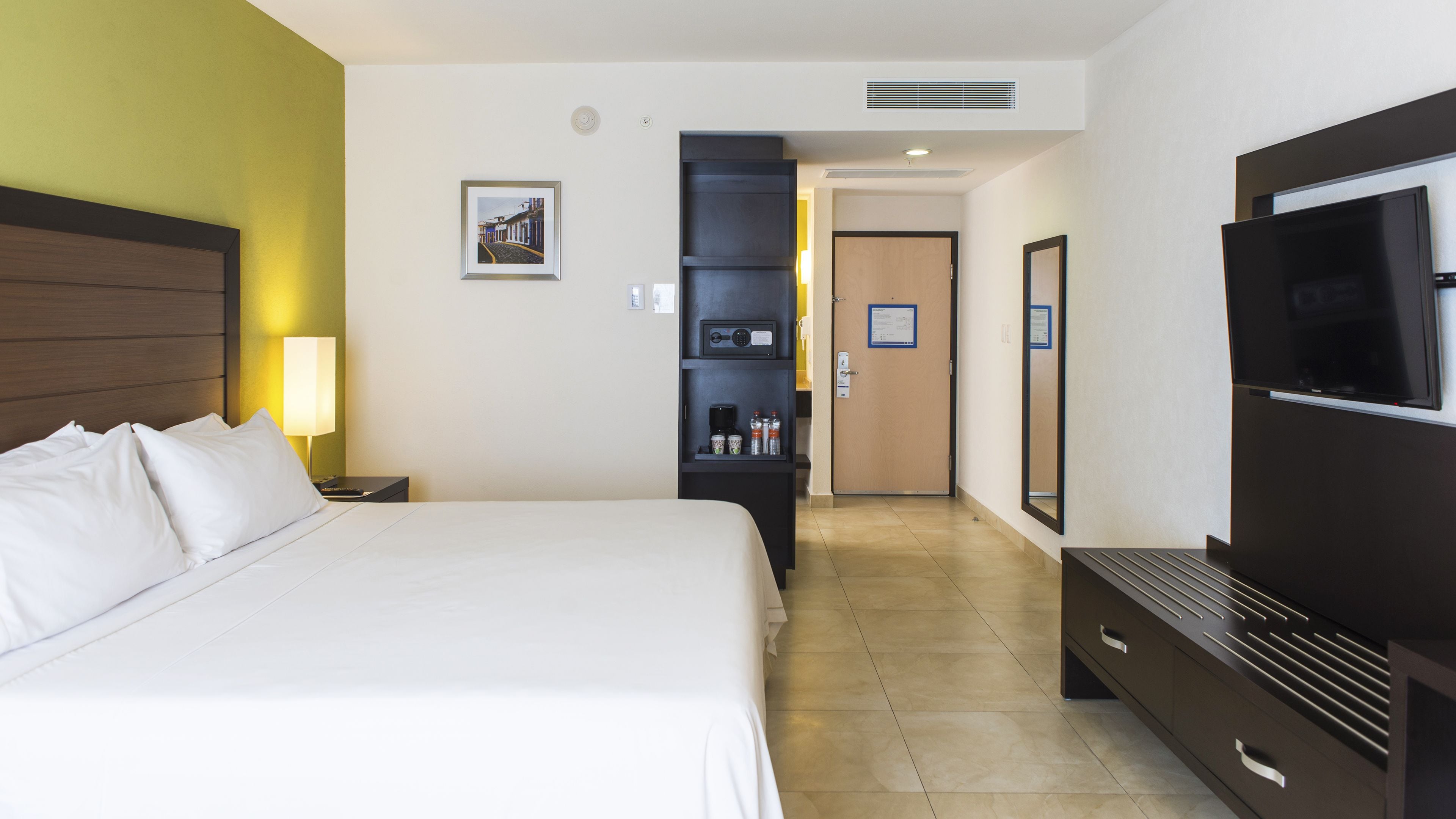 Una habitación de hotel con una cama grande, televisión, escritorio y minibar.