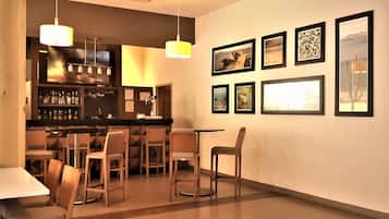 A bar area with a counter, multiple chairs, and framed pictures on the wall.