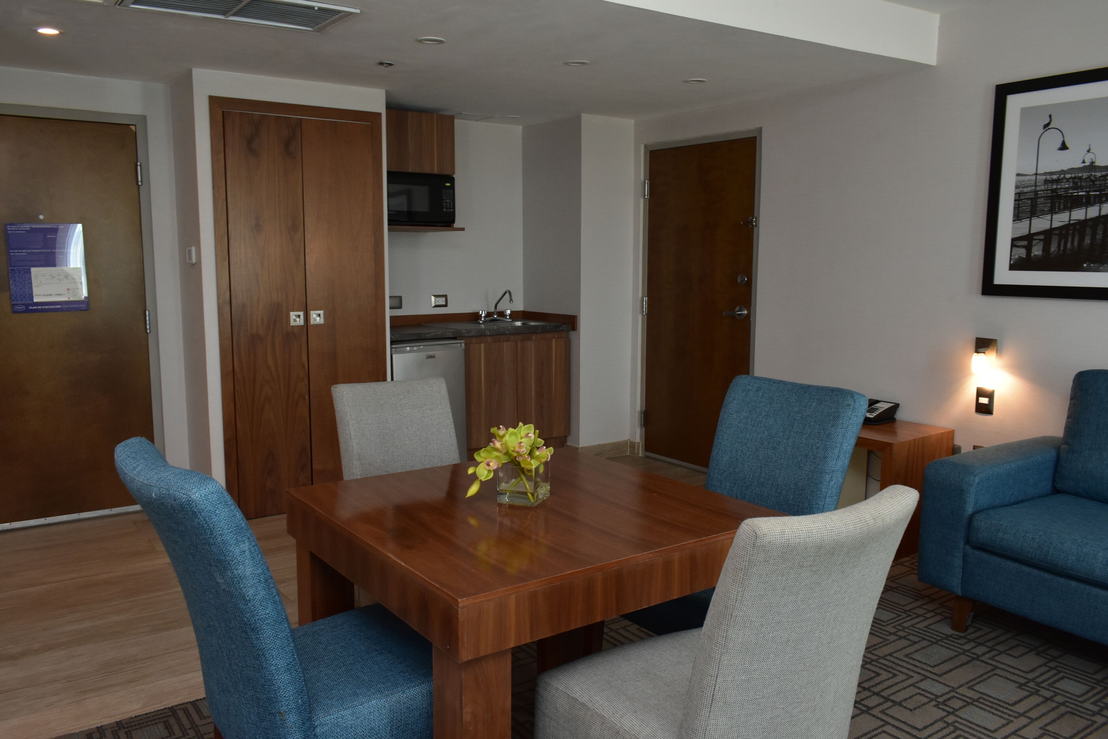 A dining area with a wooden table, blue upholstered chairs, and a vase with flowers.