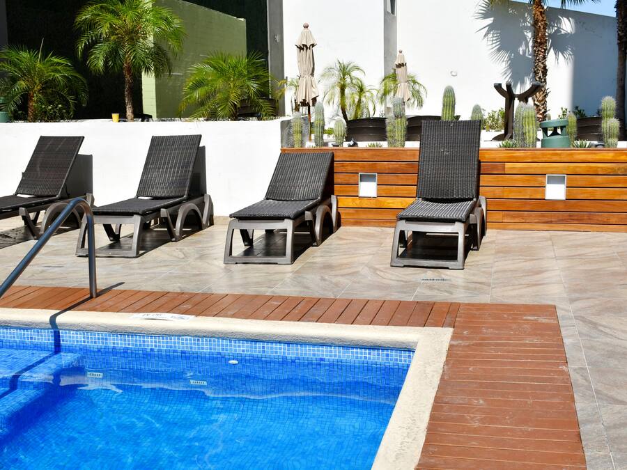 A poolside area with lounge chairs, a pool, and decorative plants.