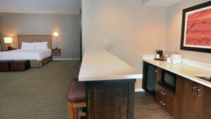 A hotel room with a bed, bedside lamps, a desk with a sink, and a framed picture on the wall. - Hampton Inn Springfield-Southeast (Springfield)