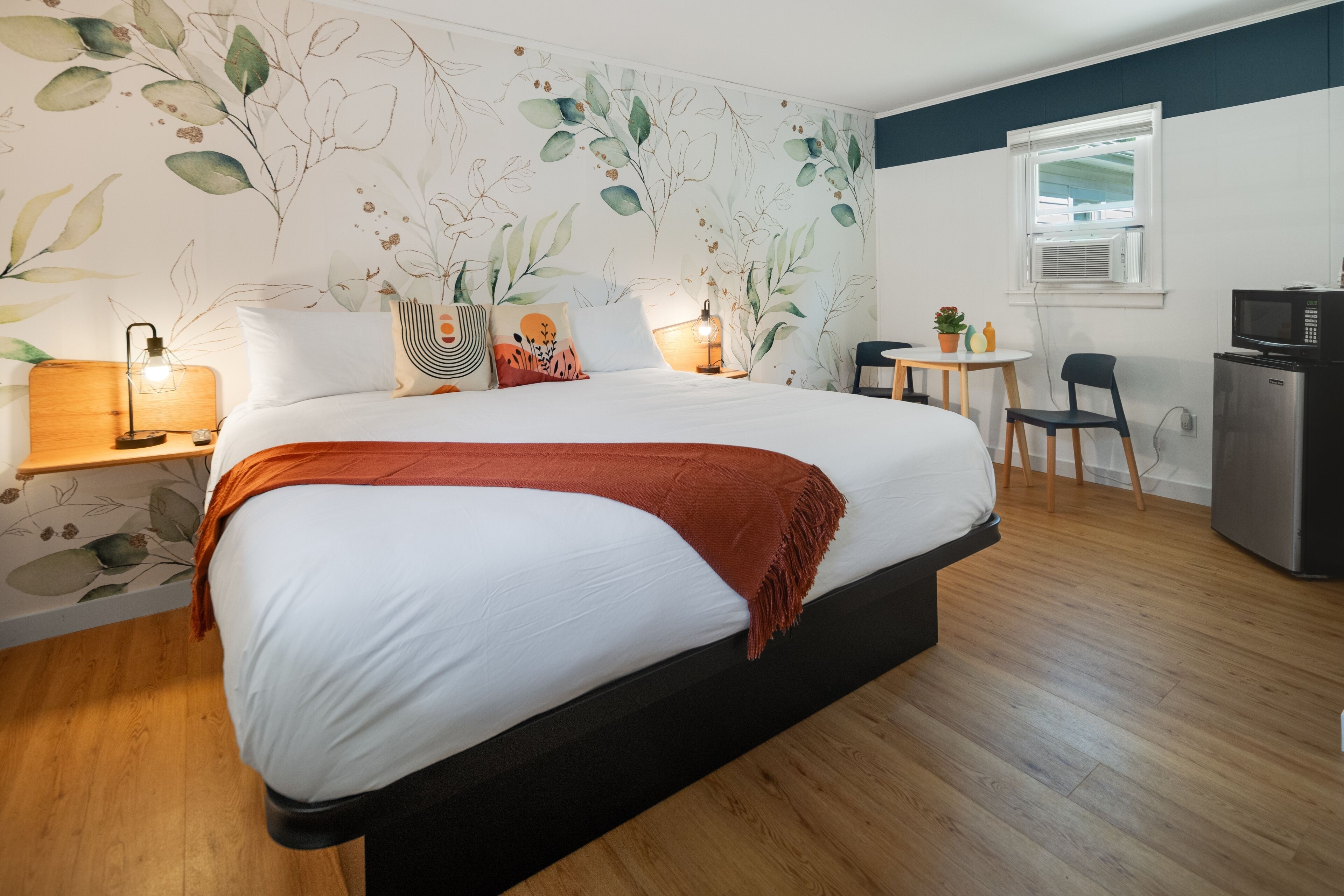 Ein Schlafzimmer mit einem großen Bett, einem Schreibtisch, einem Stuhl und einem Kühlschrank.
