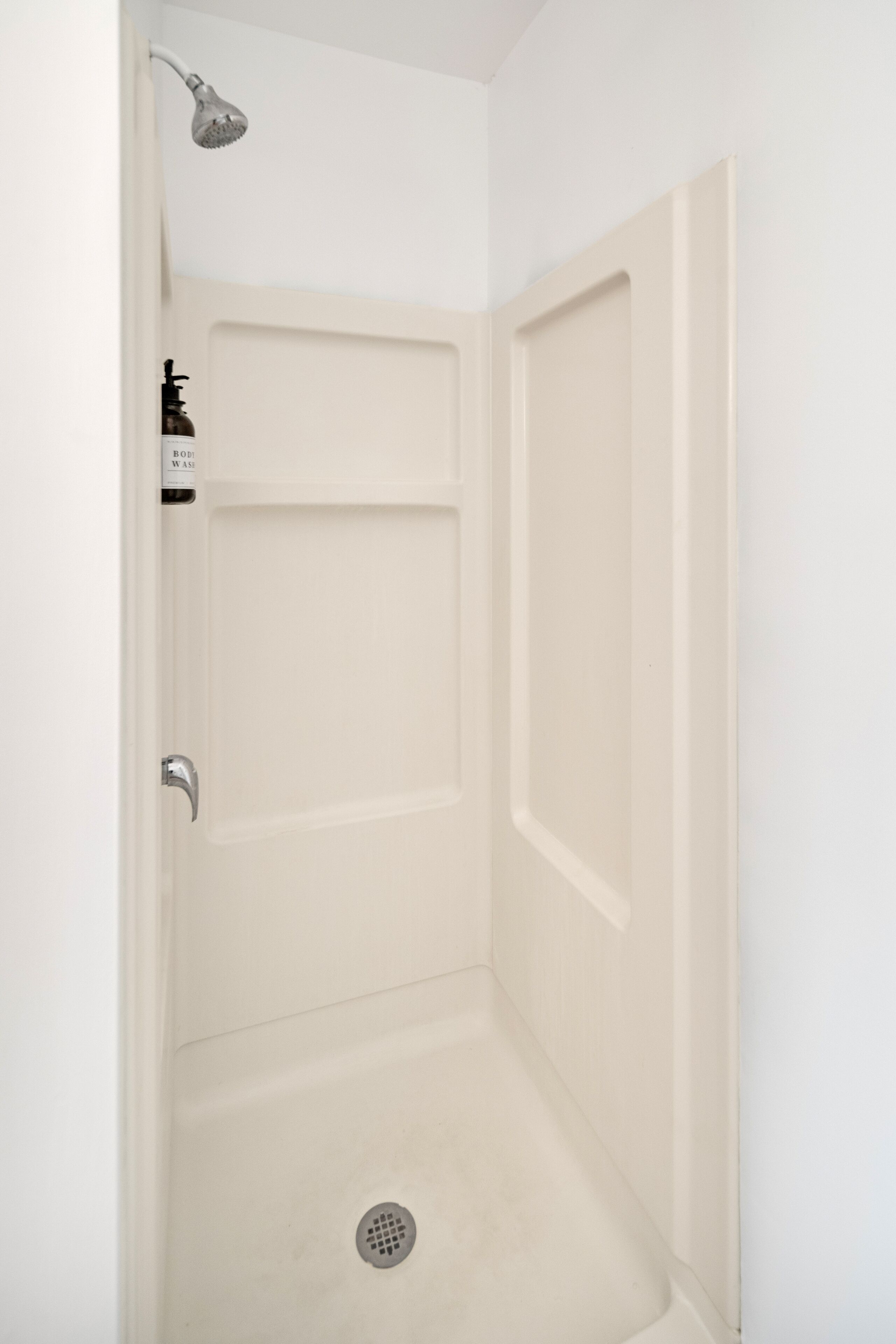 A white bathroom with a shower, a toilet, and a sink.
