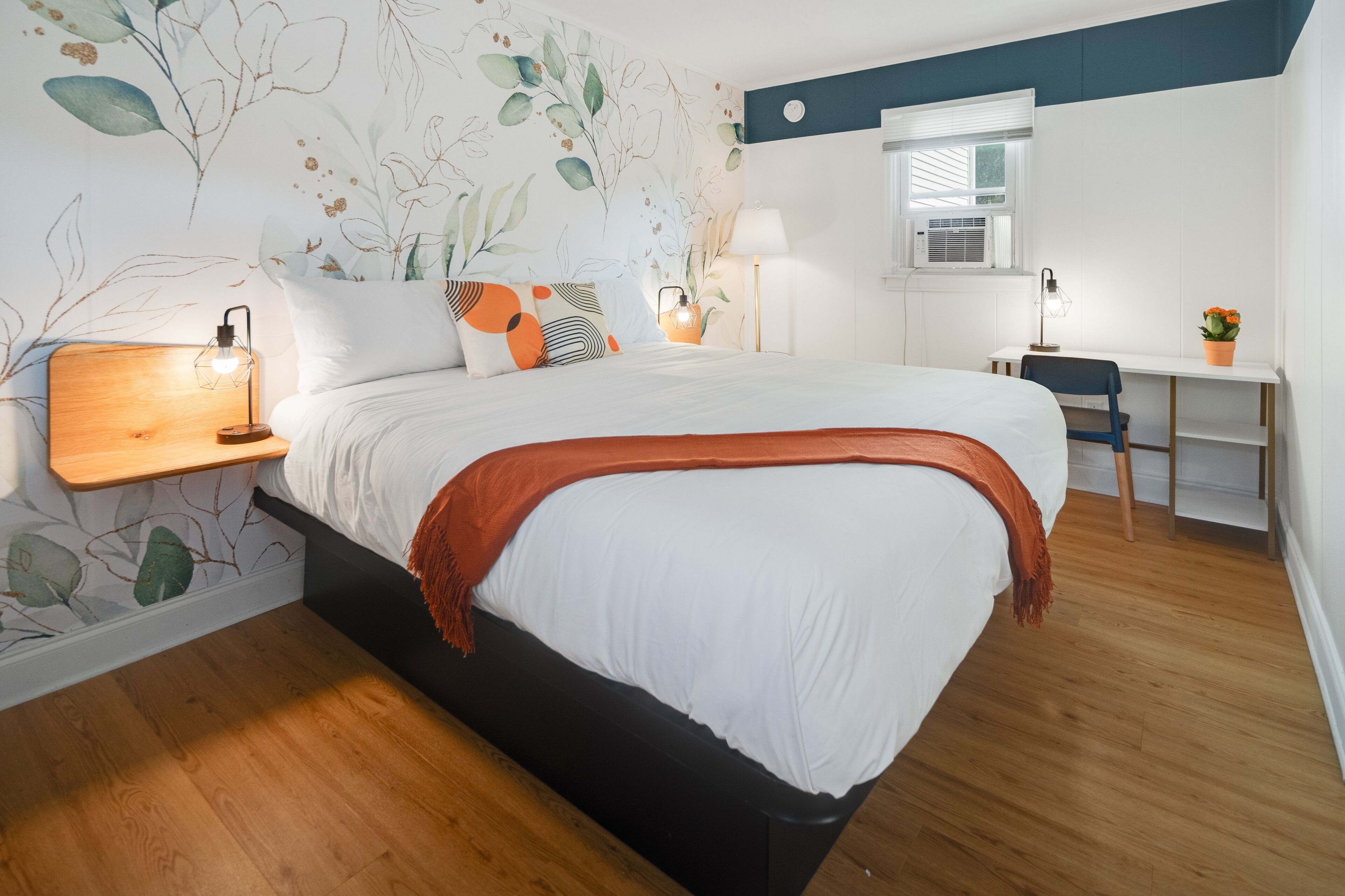 A bedroom with a bed, bedside tables, a desk, and a chair.