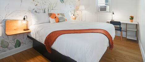 A bedroom with a bed, bedside tables, a desk, and a chair.