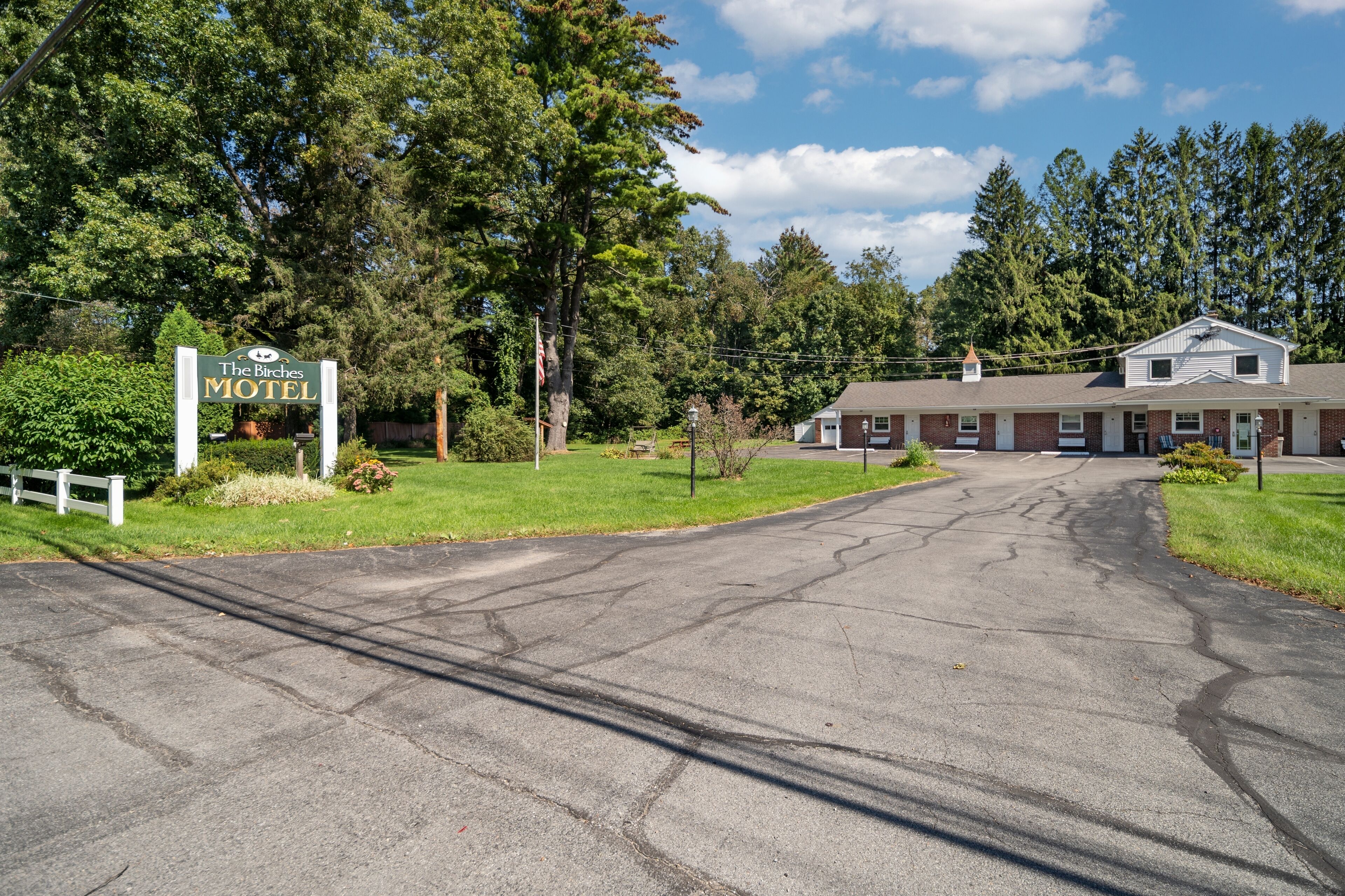 A motel with a signboard, a paved driveway, and a building with a gabled roof.