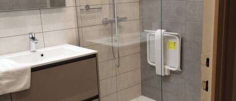Un baño moderno con ducha de vidrio, lavamanos blanco y espejo.