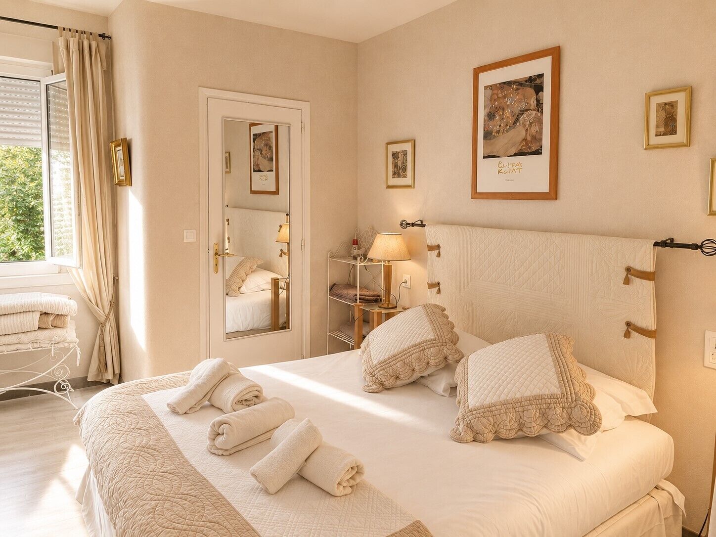 Habitación de hotel con cama, mesita de noche con lámpara, espejo y ventana con cortinas.