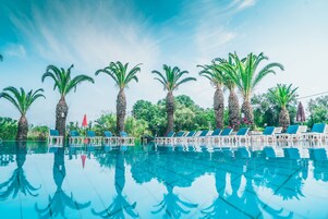 Una piscina al aire libre, sombrillas, sillones reclinables de piscina