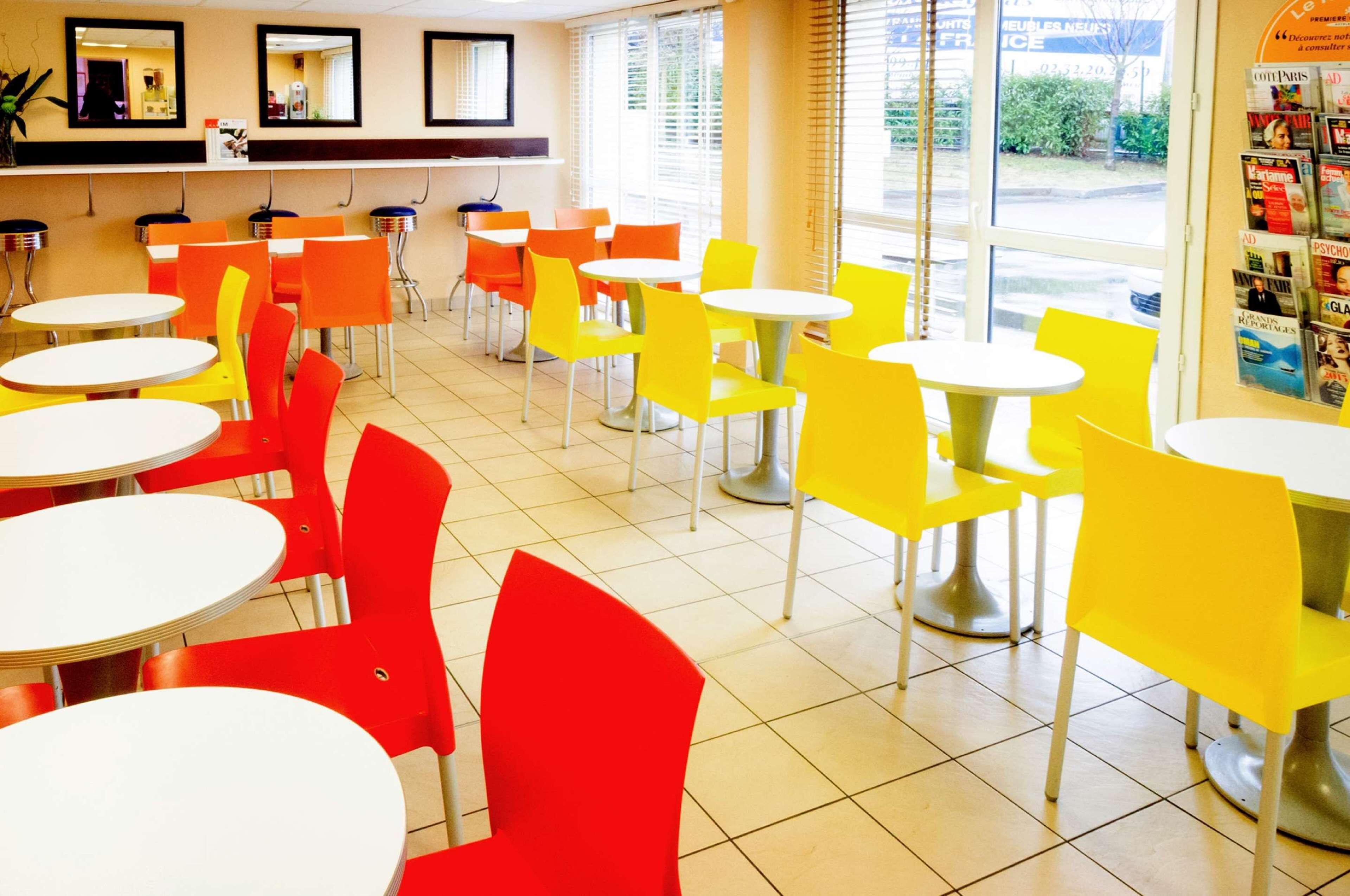 Un espace intérieur lumineux, agrémenté de plusieurs tables rondes et de chaises aux couleurs rouge et jaune.