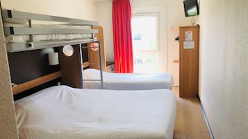 A hotel room with two single beds, a bunk bed, a wooden wardrobe, a television mounted on the wall, and a window with red curtains.