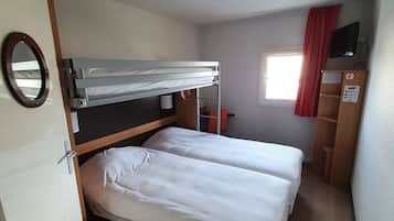 Habitació petita amb una llitera, escriptori, mirall i finestra amb cortines.
