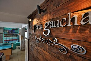 Pared de madera con el letrero "Tierra Gaucha" y decorativos remolinos de metal.