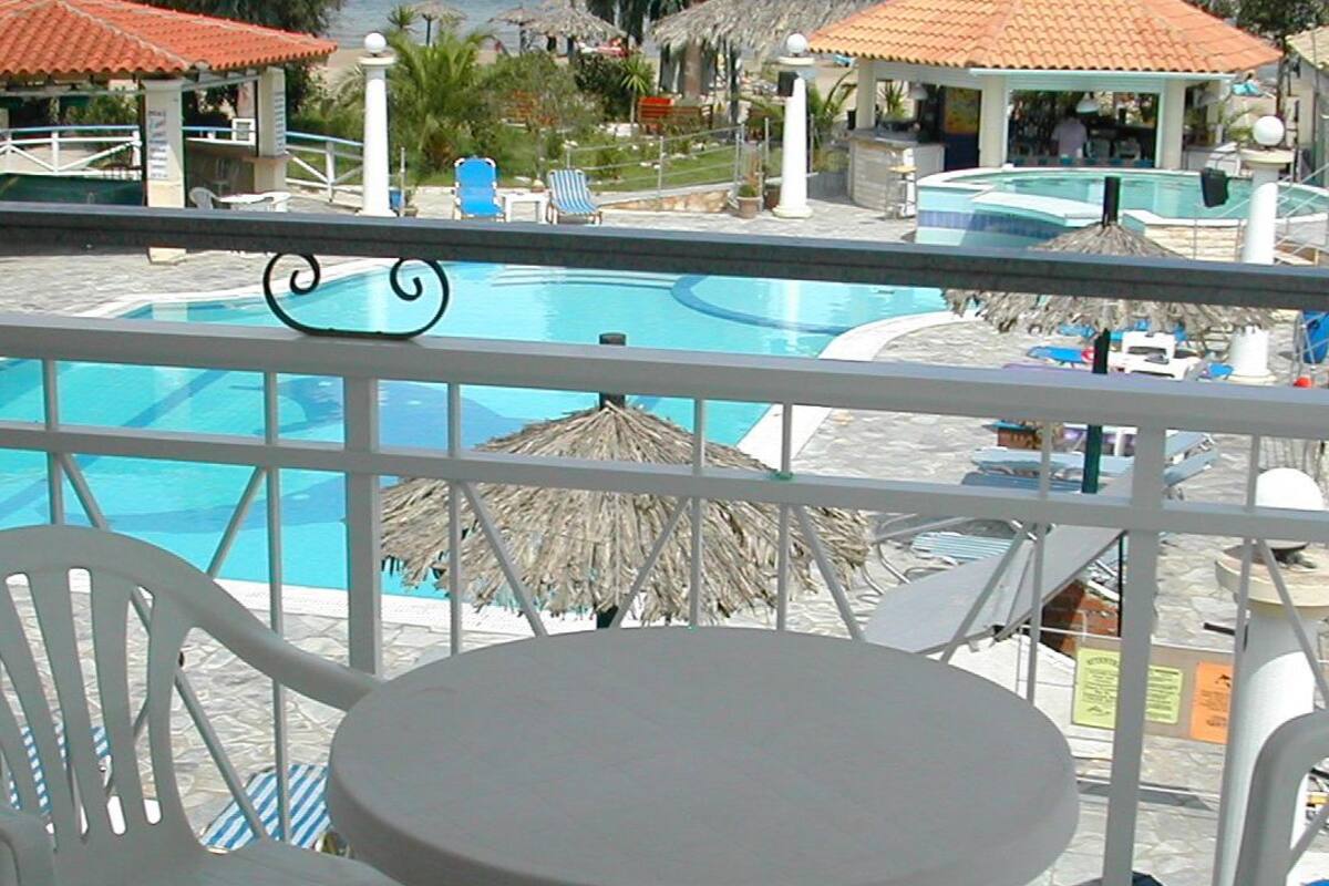 A pool area with a table and chairs, surrounded by umbrellas and lounge chairs.