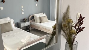 Une chambre moderne avec deux lits, un grand miroir et un vase contenant des fleurs séchées.