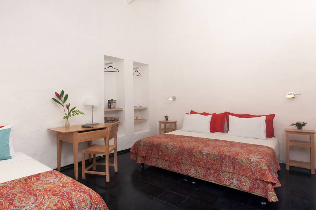 A hotel room with two beds, a desk, a chair, and a small table.