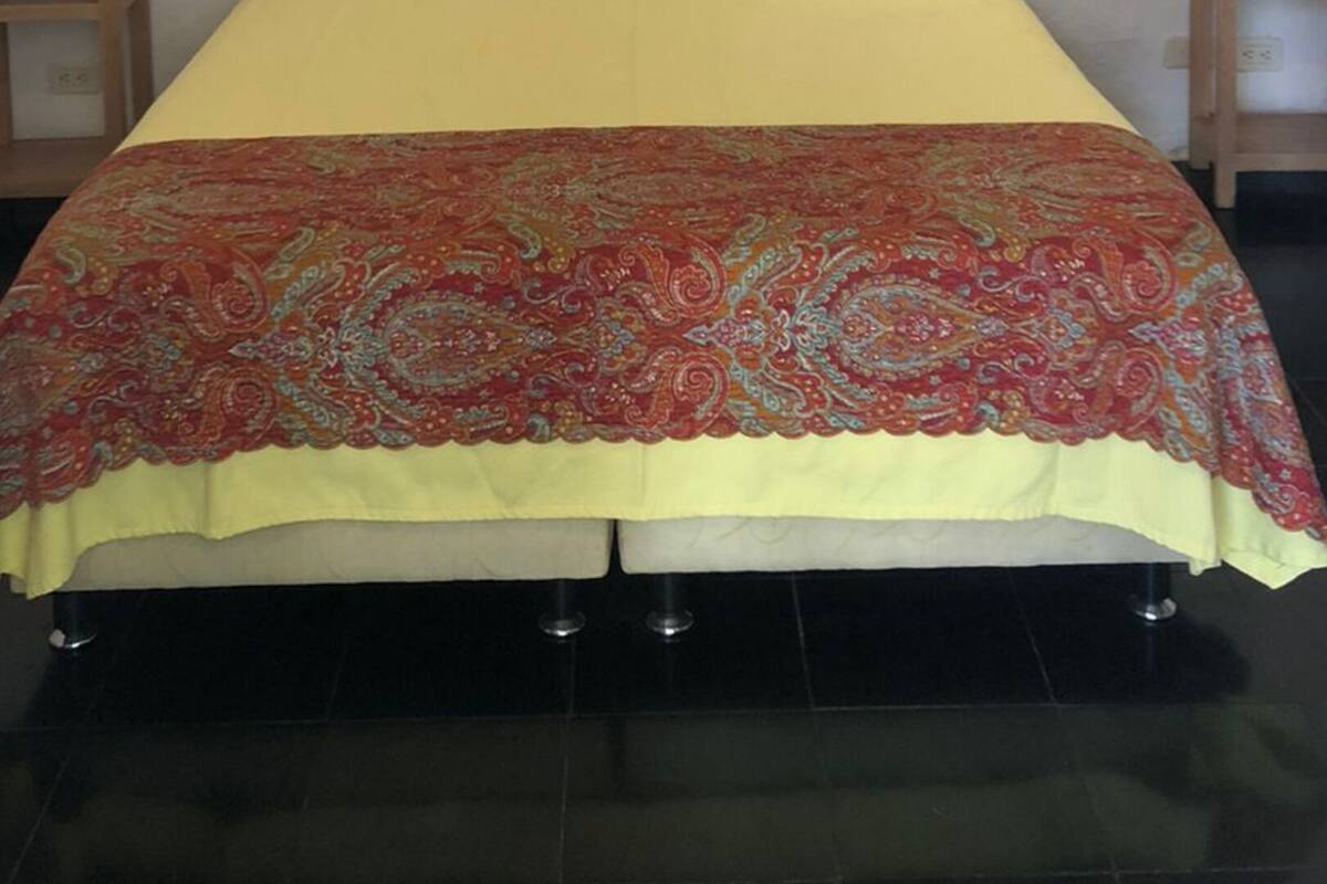 A bed with a patterned bedspread, two bedside tables, and wall-mounted lights.