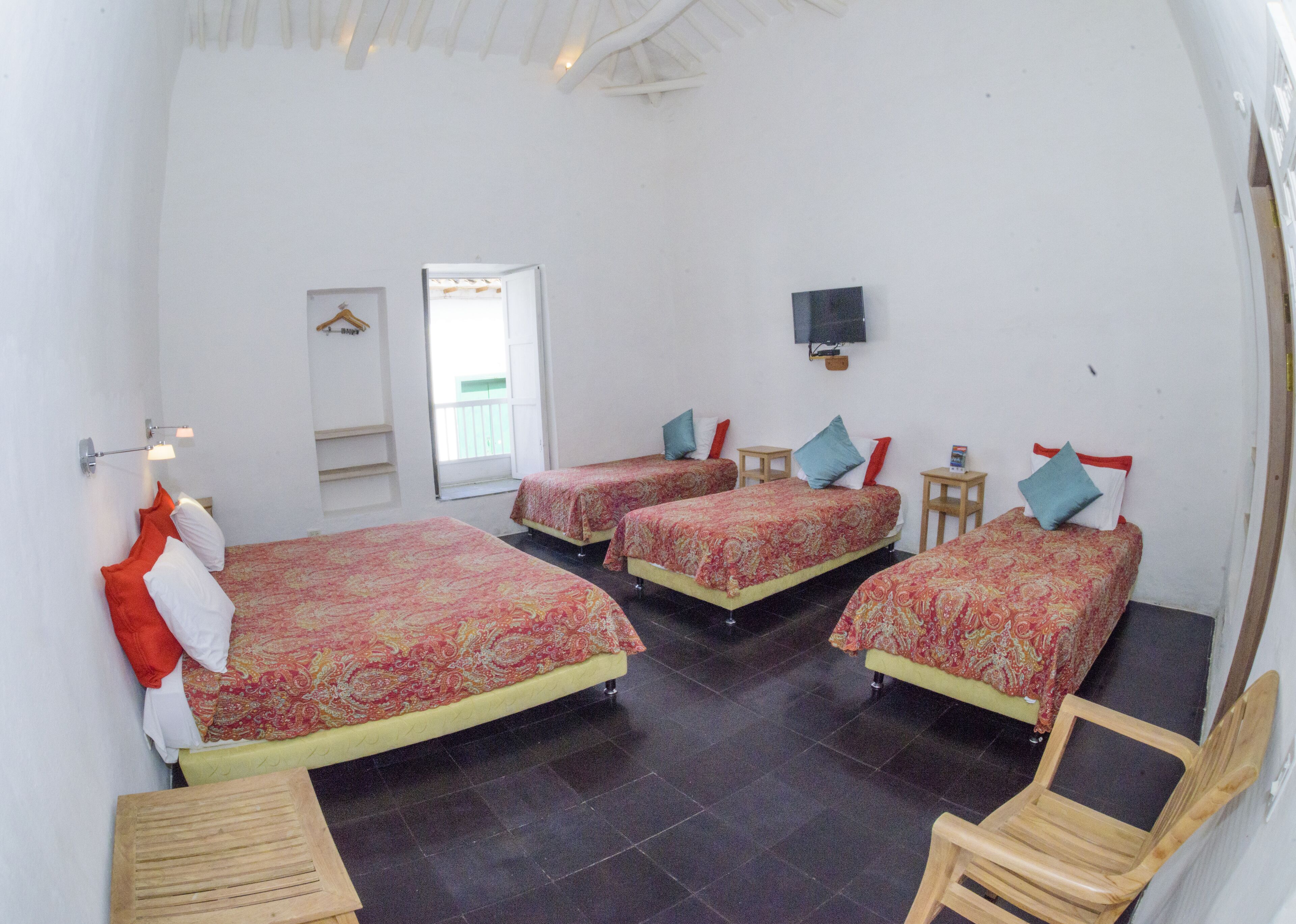 Una habitación con tres camas, televisión y una mesita.