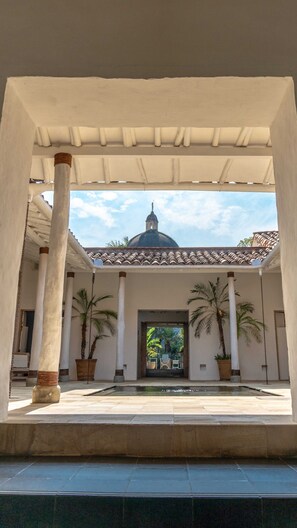 Une cour avec une fontaine, des palmiers et, au fond, un bâtiment surmonté d’un dôme.