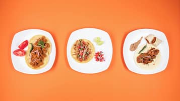 Three white plates with different food items on an orange background.