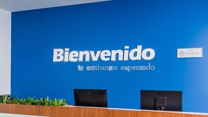 Un comptoir d’accueil avec un mur bleu et une pancarte sur laquelle on peut lire : « Bienvenido, nous vous attendons ».