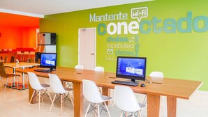 Une salle de conférence équipée de deux écrans d’ordinateur, de chaises blanches et d’un mur vert sur lequel est inscrit du texte.