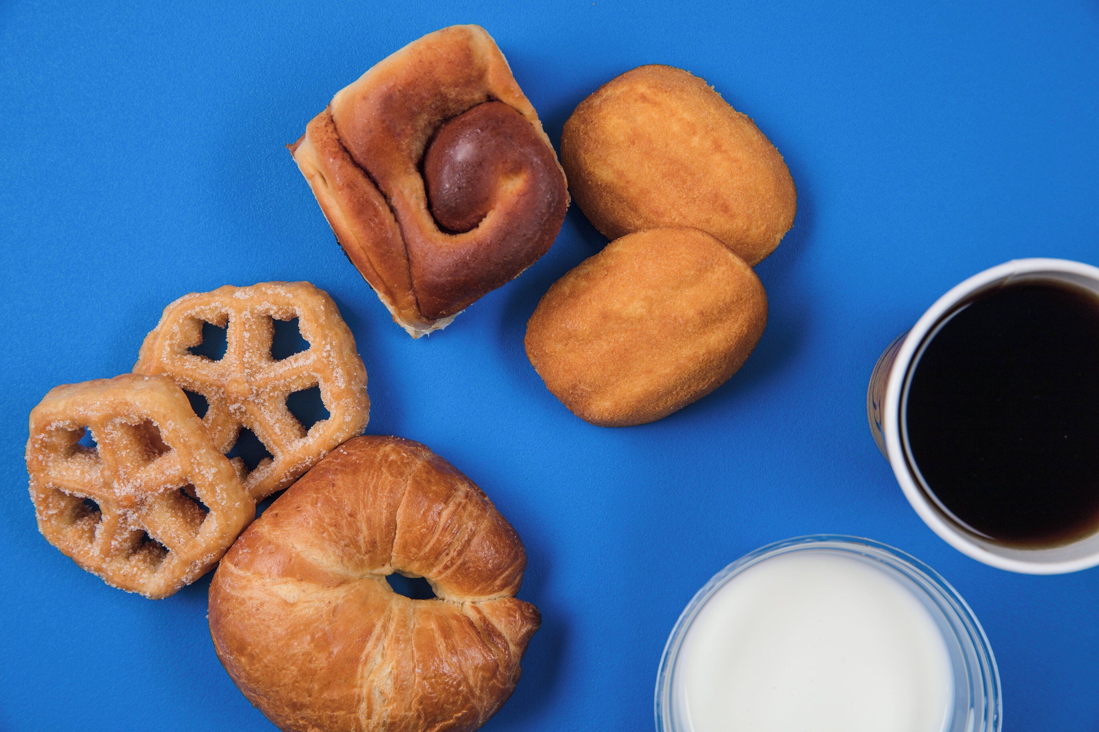 Variedad de pasteles y una taza de café sobre un fondo azul.