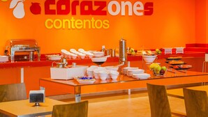 Un espace buffet avec un mur de couleur orange vif, une variété de plats et une machine à café.