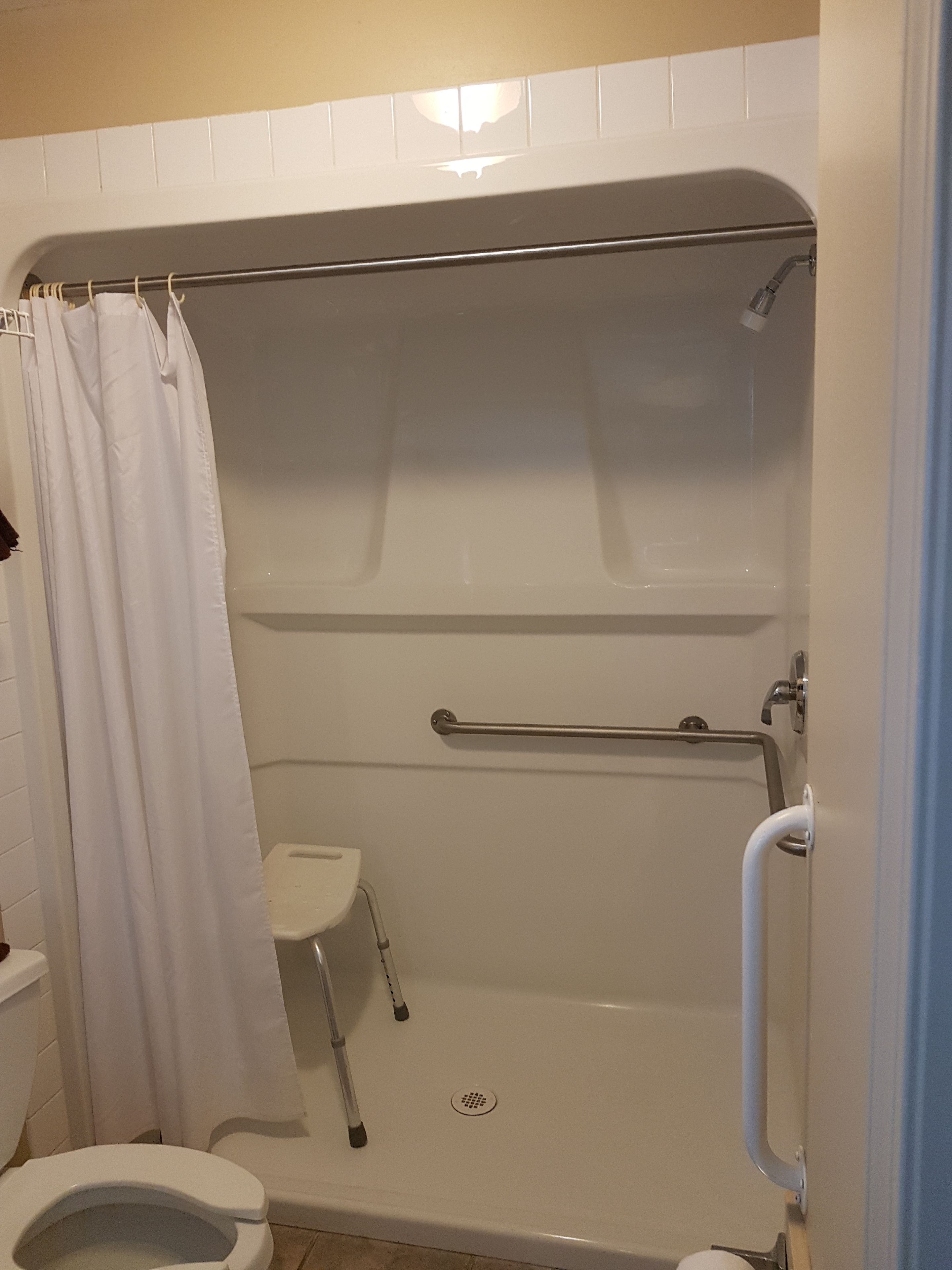 Une salle de bain équipée d’une douche, de toilettes et d’une barre d’appui.