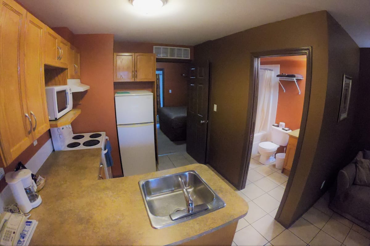 A compact kitchen with a sink, stove, microwave, and refrigerator.