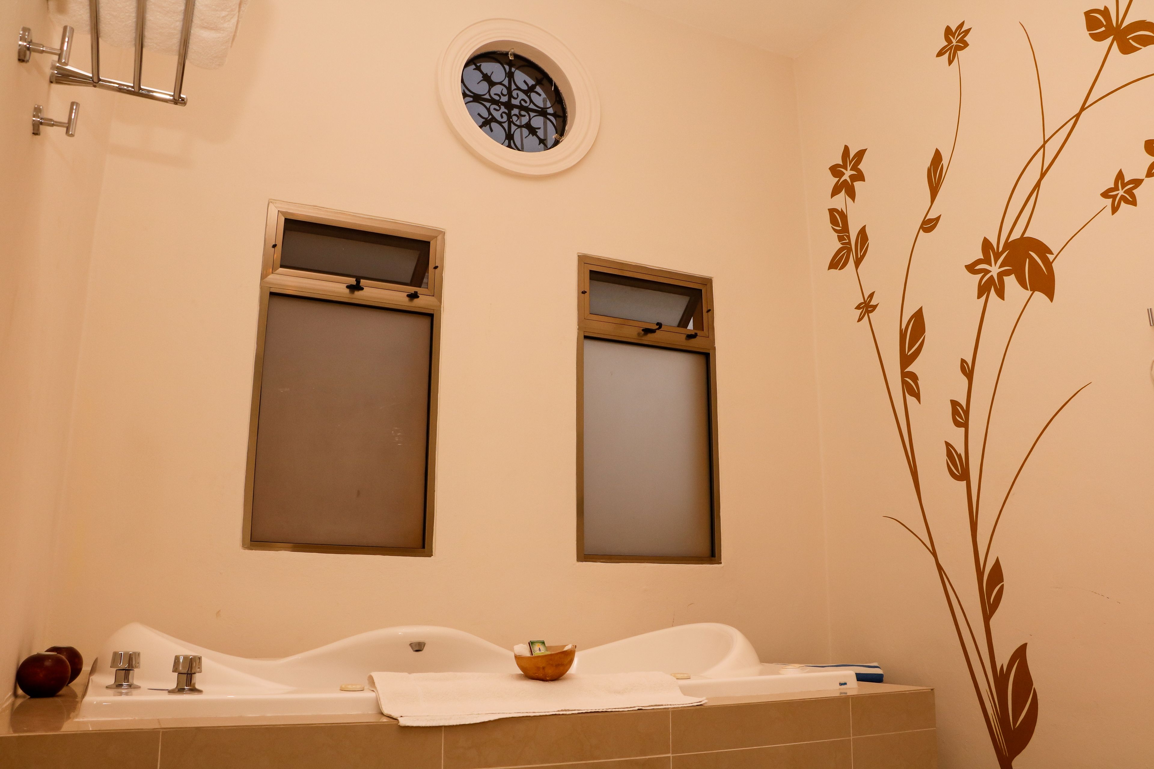 Un baño con dos ventanas, una bañera y un perchero de pared.