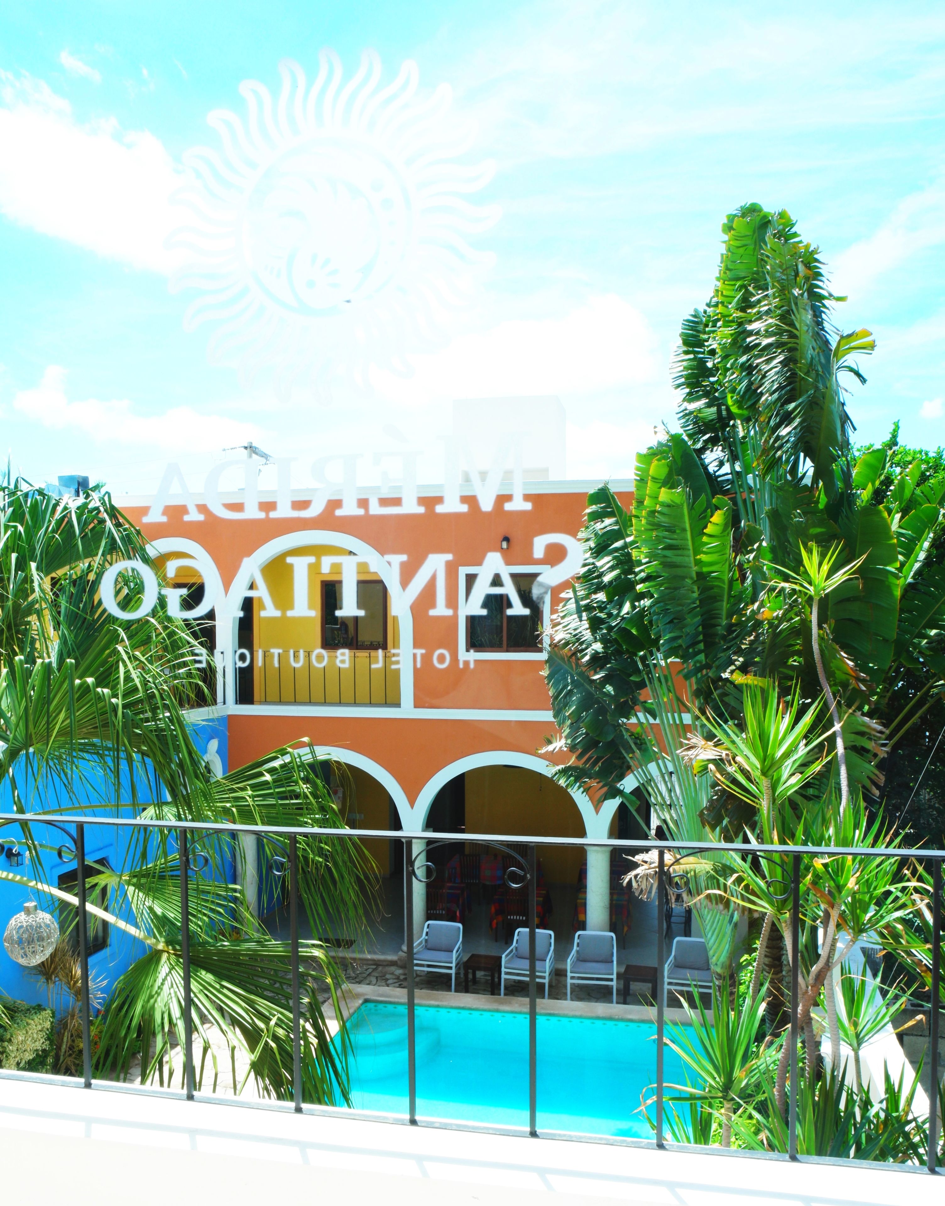 Un hotel con piscina, rodeado de palmeras y un cielo azul despejado.
