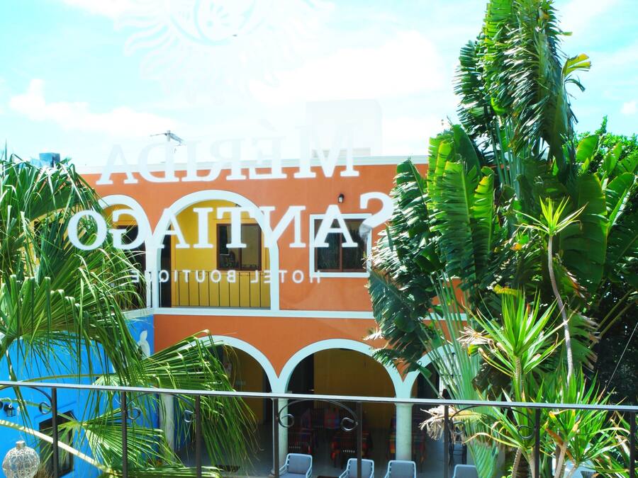 Un hotel con piscina, rodeado de palmeras y un cielo azul despejado.