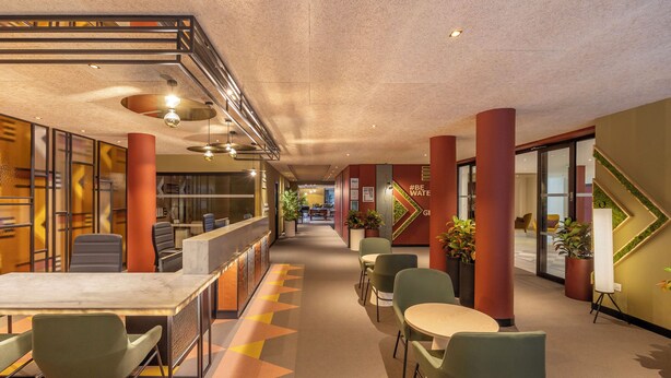 A modern hotel lobby with a reception desk, seating area, and a staircase. - Royal Regency Paris Vincennes (Vincennes)