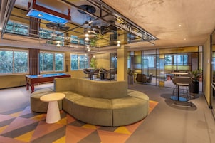 Un espacio interior moderno con mesa de billar, sofá seccional y mesa de futbolín.