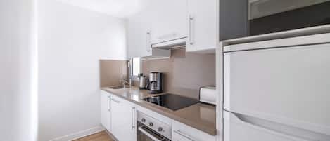 Eine moderne Küche mit weißen Schränken, einem eingebauten Backofen, einer Kaffeemaschine und einem Toaster.