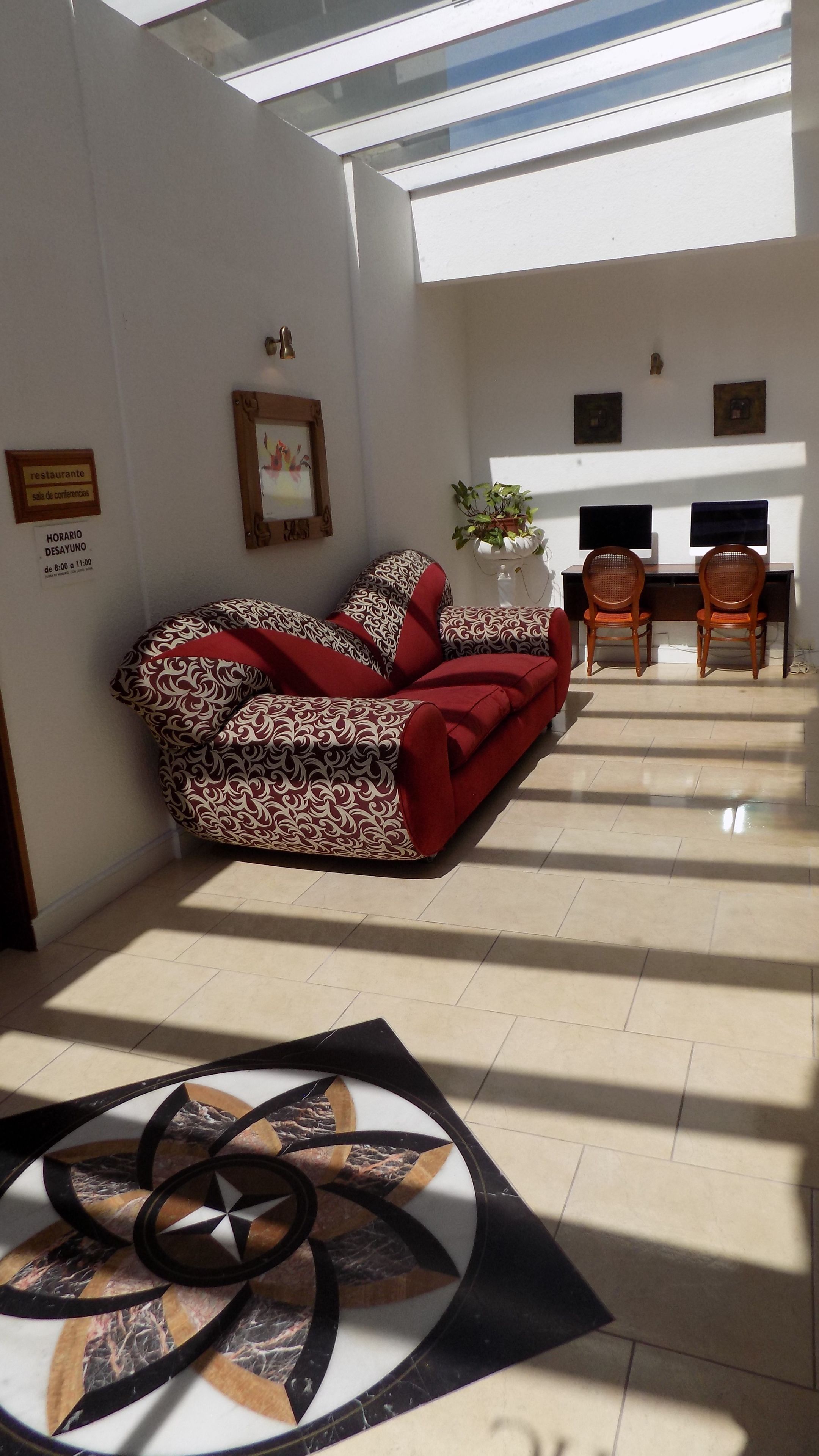 Ein Wohnzimmer mit einem gemusterten Sofa, einem Couchtisch mit geometrischem Design, einem Kamin und einem Essbereich mit zwei Stühlen.
