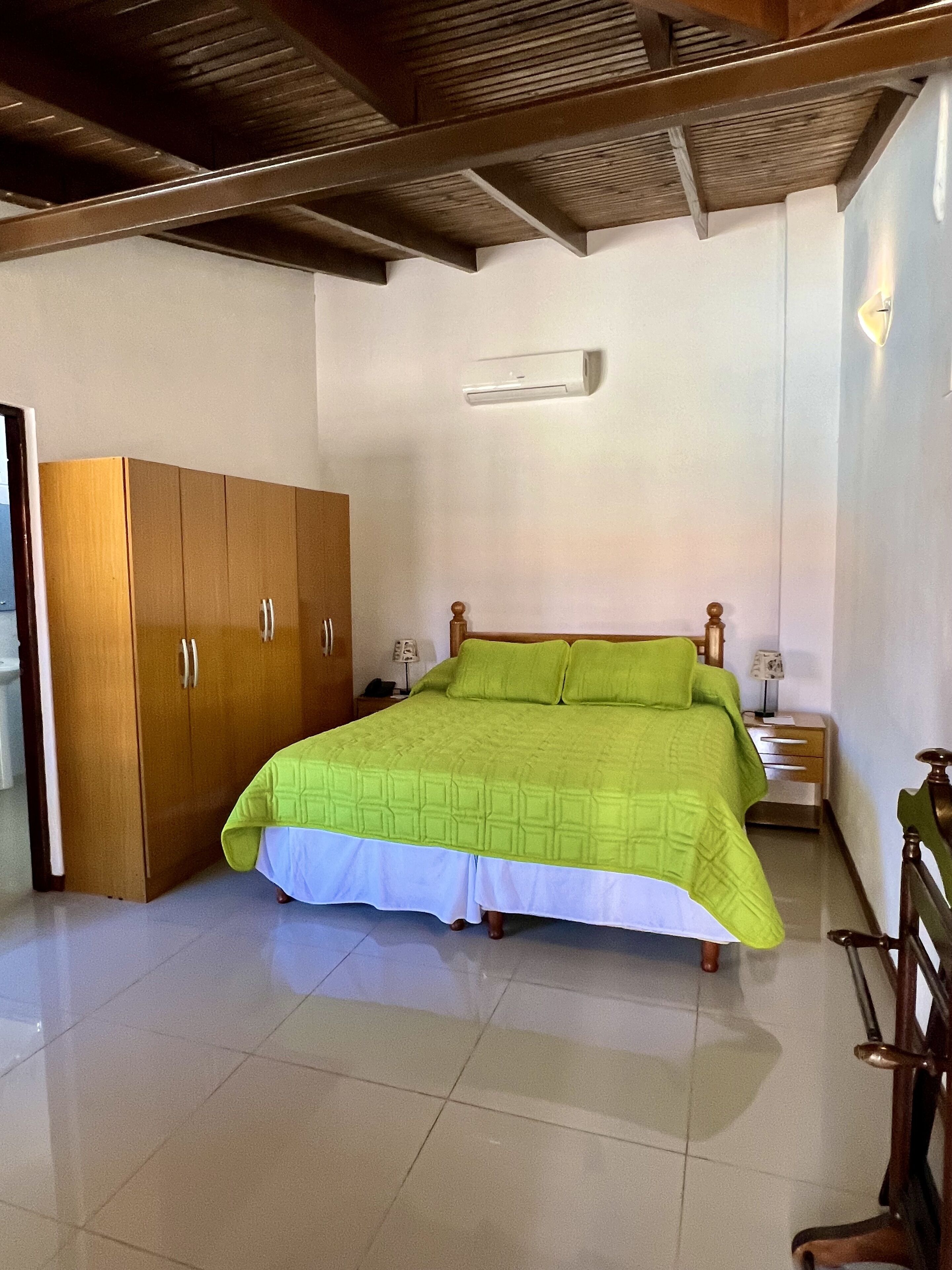 A bedroom with a bed, wooden wardrobe, bedside tables, and a ceiling fan.