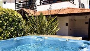 A swimming pool with a wooden deck, surrounded by white buildings with red-tiled roofs and balconies. - Hotel Concorde (Punta del Este)