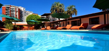 Una piscina al aire libre, sillones reclinables de piscina