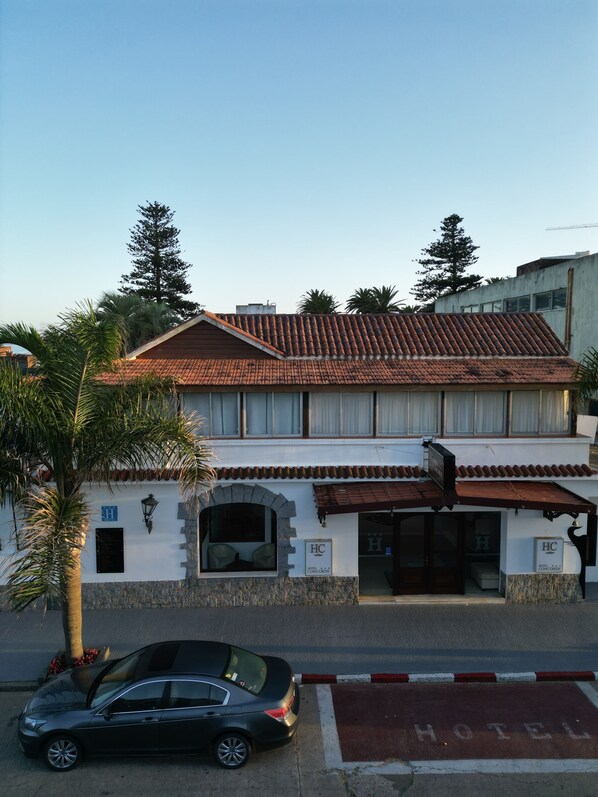 A two-story building with a tiled roof, a stone facade, and a sign indicating it is a hotel.