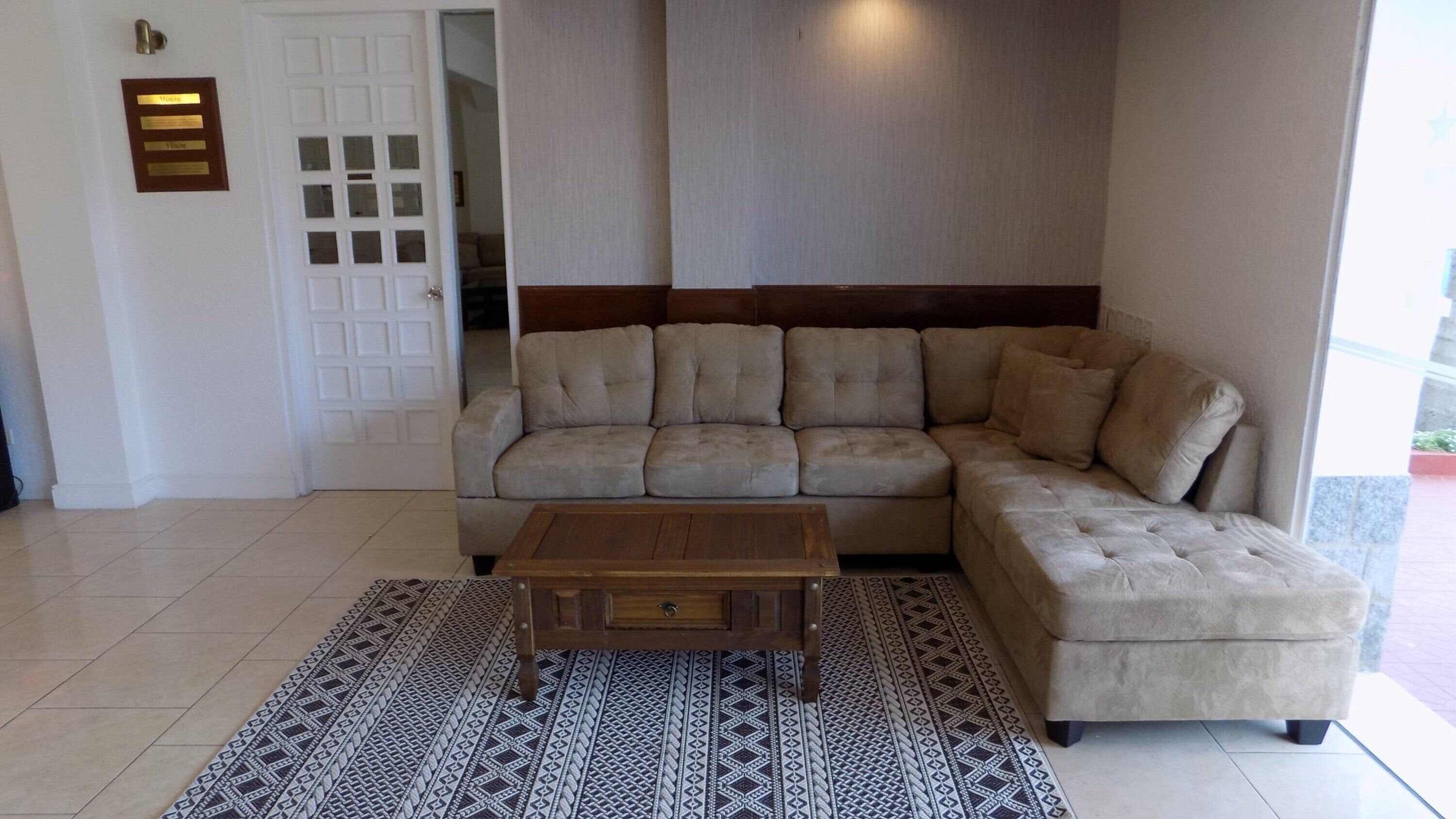 En stue med en beige modulsofa, et træbord og farverige tæpper.