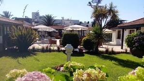 A courtyard with a lawn, outdoor seating, and umbrellas. - Hotel Concorde (Punta del Este)