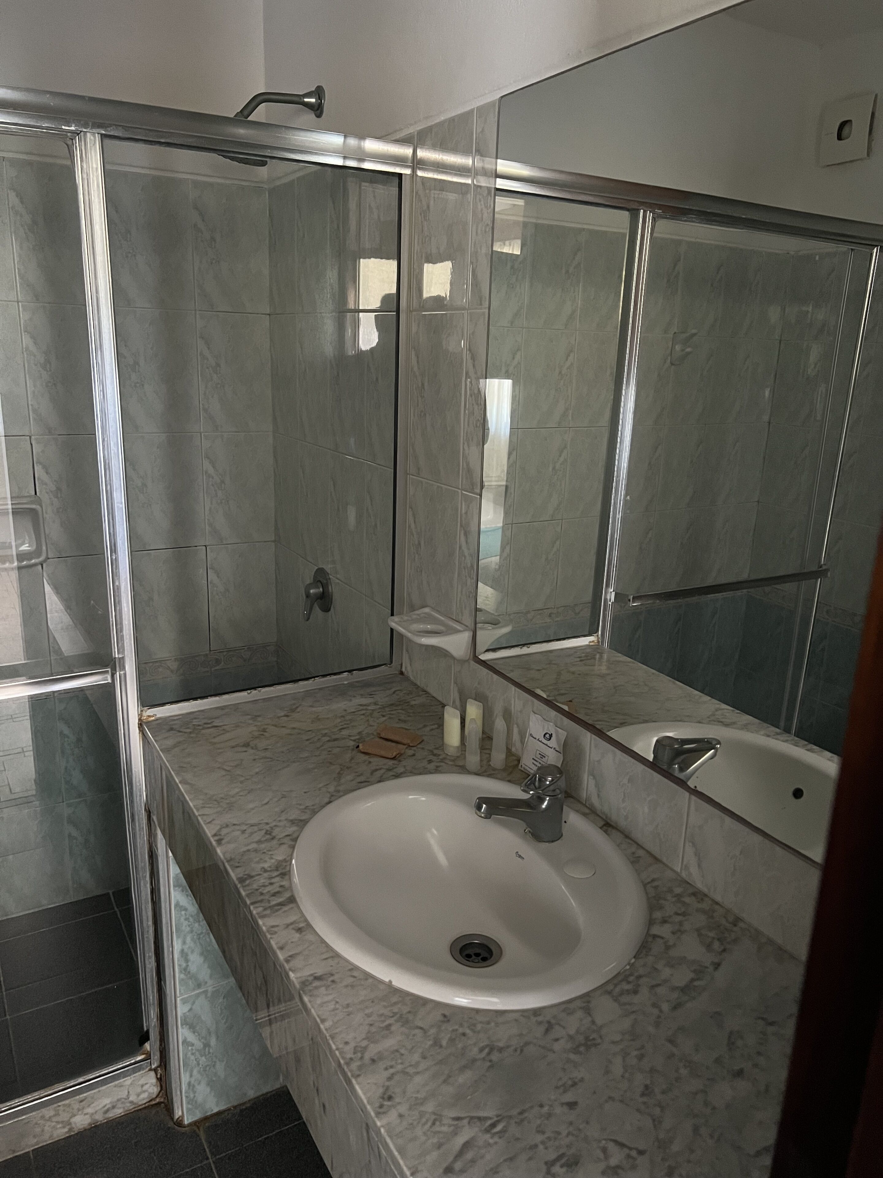 Un baño moderno con cabina de ducha de vidrio, un lavabo blanco y un espejo grande.