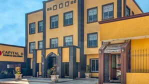 Un edificio de varios pisos con fachada amarilla, marcos de ventanas negros y una entrada central con arco negro.