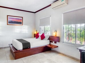 Une chambre d’hôtel équipée d’un lit, de tables de chevet, d’une fenêtre avec vue et d’un appareil de climatisation.