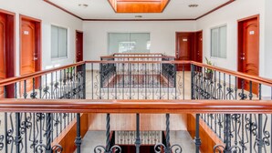 Un interior espacioso con una escalera de madera, un área central abierta y varias puertas.