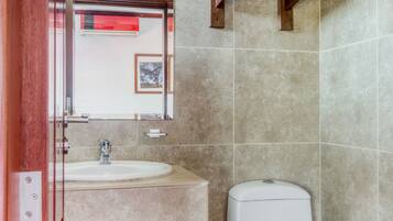 Une salle de bain équipée d’un lavabo, de toilettes et d’un porte-serviettes.